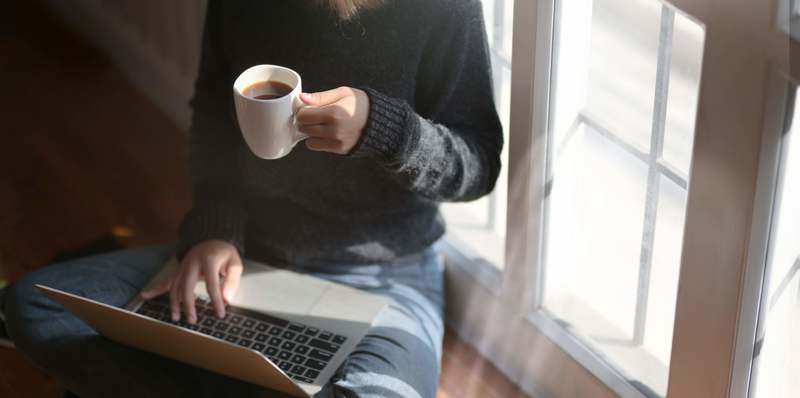 Woman Using Laptop While Holding A Cup Of Coffee 3759083 (1)